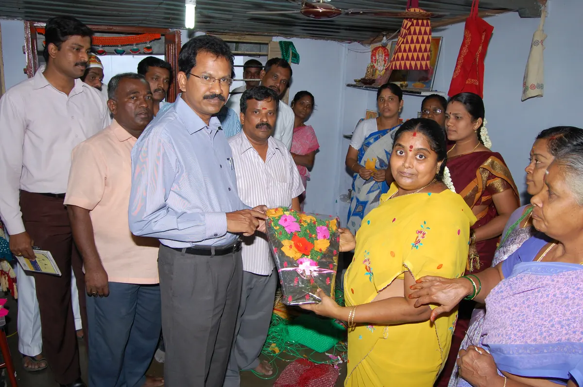 Women artisans presenting framed craft bouquet to Theni District Collector Mr. Palanichamy