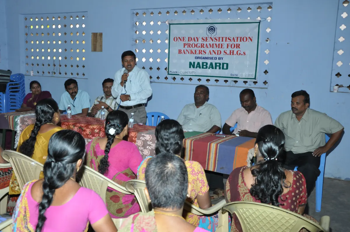 Official addressing women SHG members under NABARD training programme banner